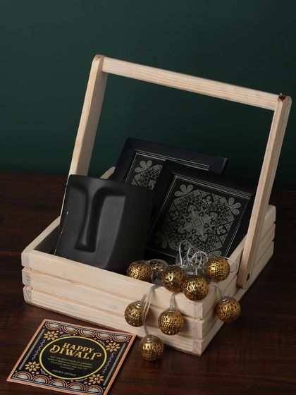 For a modern and artistic touch, this hamper features a unique face-planter mug. It's paired with premium chocolates and decorative lights, all presented in a rustic wooden basket.