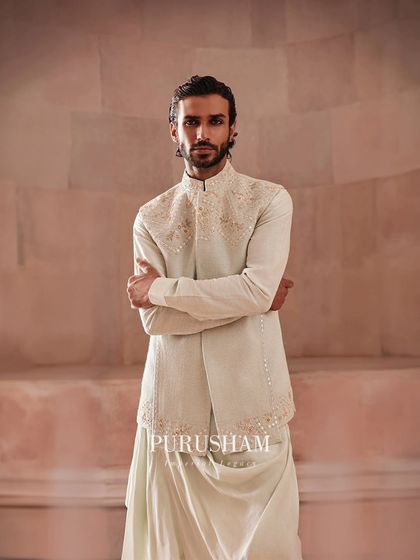 A modern interpretation of traditional wear. This layered look features an embroidered jacket over a draped kurta, offering a stylish and comfortable option for pre-wedding festivities or a contemporary ceremony.