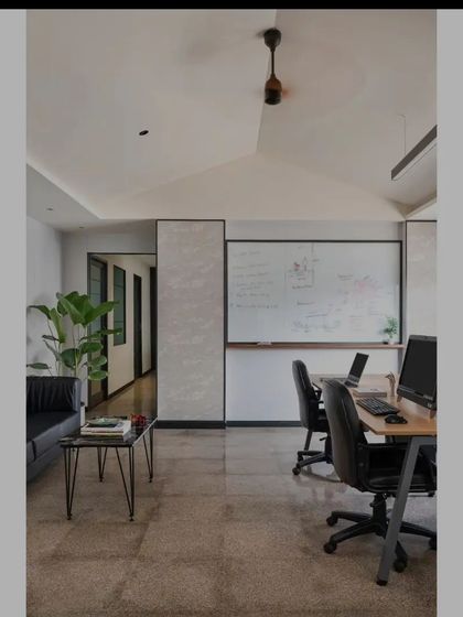 The main workstation area in Project Rooftop, showing the dramatic gabled ceiling and the clean, open layout. The polished concrete floor and white walls create a neutral canvas, while the large whiteboard is ready for brainstorming and creative sessions.