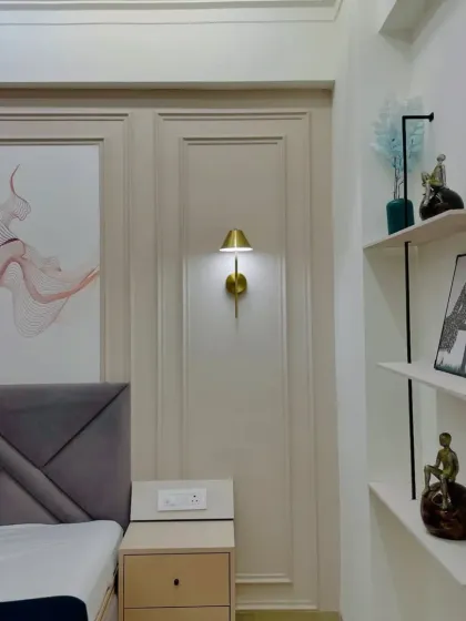 Details of the bedroom decor, including the modern wall sconce and the open-shelf unit for displaying decorative items.