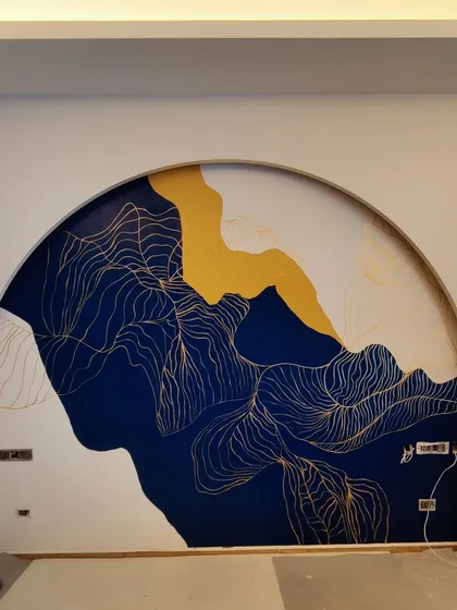 Abstract art allows for a unique expression of mood and style. This piece, set within a grand arch in a luxury bedroom, uses bold strokes of blue, ochre, and delicate gold linework to create a dramatic and sophisticated accent wall.