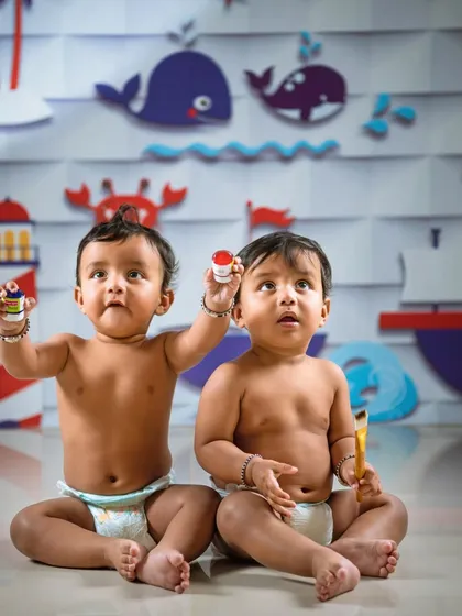 Twin babies exploring during a themed photoshoot. The nautical backdrop and playful props create a fun and engaging environment, allowing their curious personalities to shine through.