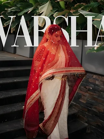 An editorial bridal shot that captures a sense of mystery and elegance. The makeup is bold yet refined, with a flawless base that glows even from under the delicate red veil, creating a powerful and memorable image.