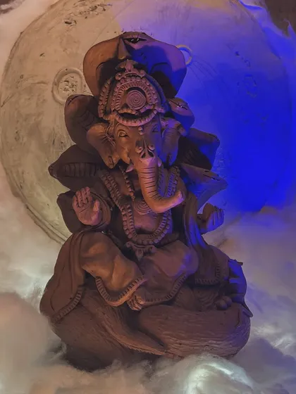 A beautifully sculpted terracotta Ganesha idol from our studio, set against a creative backdrop. We encourage celebrating with artistry and eco-conscious choices.