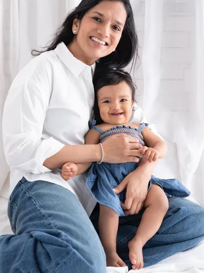 A bright and happy portrait of a mother and her smiling baby. Their coordinated outfits and genuine smiles make this a beautiful keepsake.