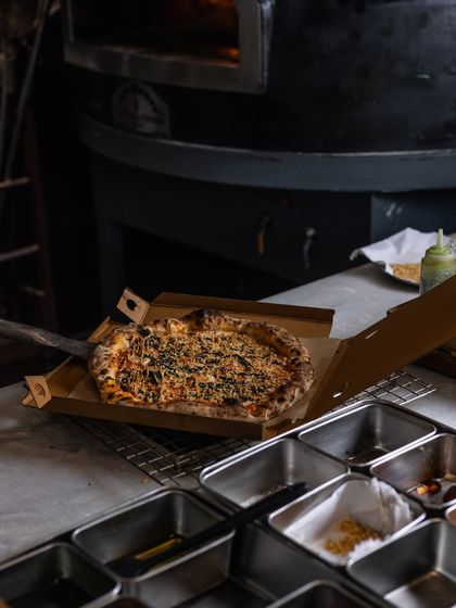 Fresh from the oven and straight into the box. This is the moment a pizza begins its journey from my kitchen to your home. I make sure it's packed securely to stay hot and delicious.