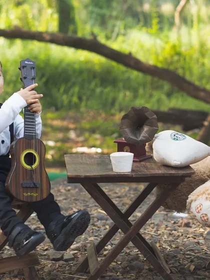 A handsome little man having a picnic with his best friend, Teddy. This outdoor setup with a miniature guitar and gramophone is full of vintage charm.