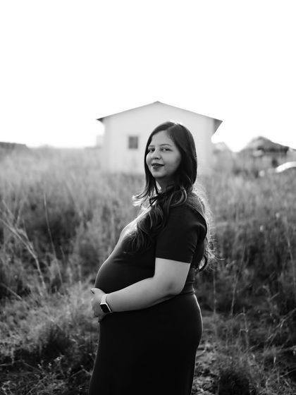 A classic black and white solo portrait of the mom-to-be in a field. Her direct gaze and the simple setting create a powerful and confident image.