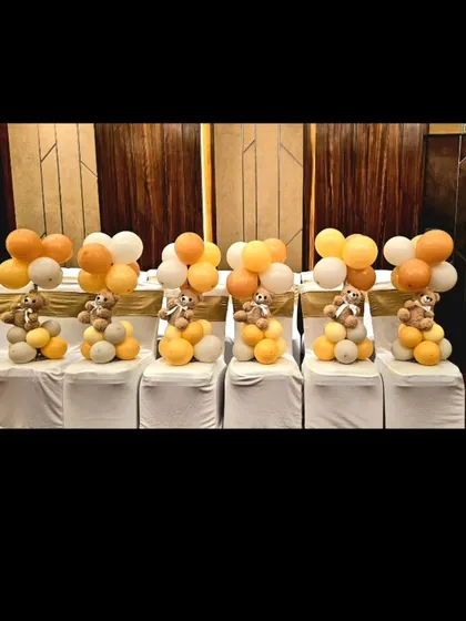 Themed table centerpieces featuring small teddy bears on top of balloon clusters, ensuring the decor theme is carried throughout the entire venue.