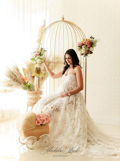 A whimsical and romantic setup featuring a golden birdcage, a vintage-style pram, and beautiful florals to complement the intricate lace gown.