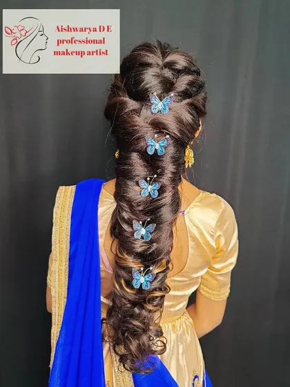 I love getting creative with hair, and this modern braided hairstyle is a great example. This intricate pull-through braid is decorated with delicate blue butterfly clips, making it a unique choice for a sangeet or reception.