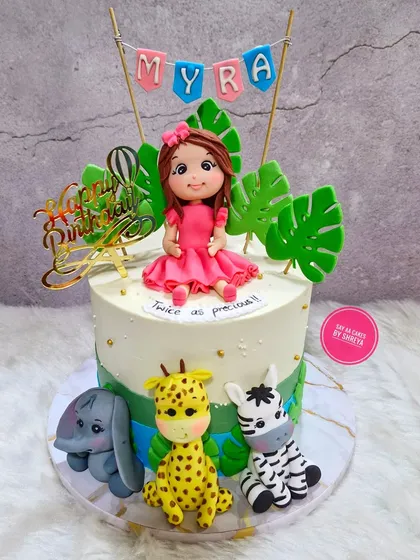 A sweet safari cake for a little adventurer's second birthday. This design features a cute, personalized girl figurine surrounded by her friendly jungle animal pals like a giraffe, elephant, and zebra.