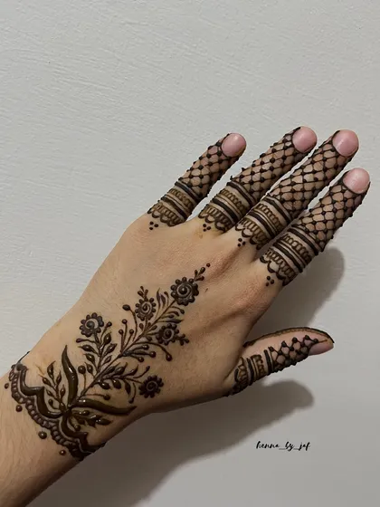 An elegant Arabic vine design that flows diagonally across the back of the hand. The pattern includes delicate floral motifs and fine latticework on the fingers, showcasing a light yet detailed style.