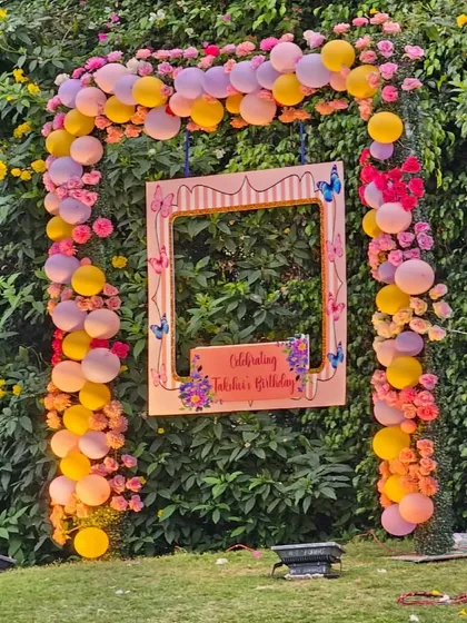 A custom photo booth frame is a great way to capture memories. For this birthday, we designed a personalized frame surrounded by a colorful balloon and flower arch against a natural green backdrop.
