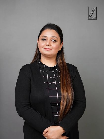 A simple and clean portrait against a grey backdrop, focusing on the subject's professional demeanor.