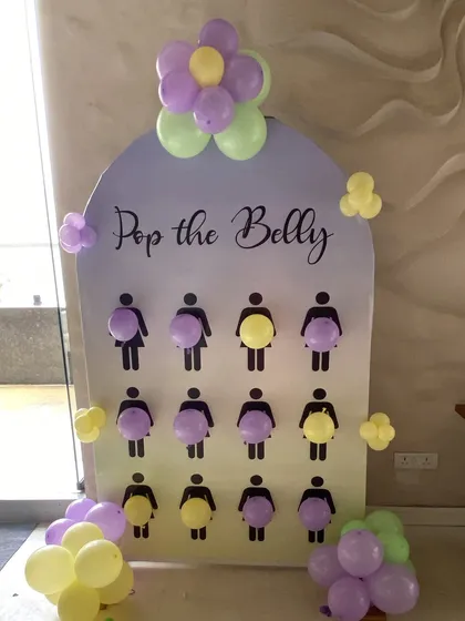 The 'Pop the Belly' game is a baby shower favorite. We created this custom board with balloons for guests to pop, all designed in the party's signature pastel purple and yellow theme.