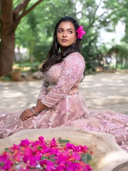 "Boss up and Gloss up." A beautiful shot from a model shoot, with a pink lehenga and a flower in her hair, creating a fresh and vibrant look.