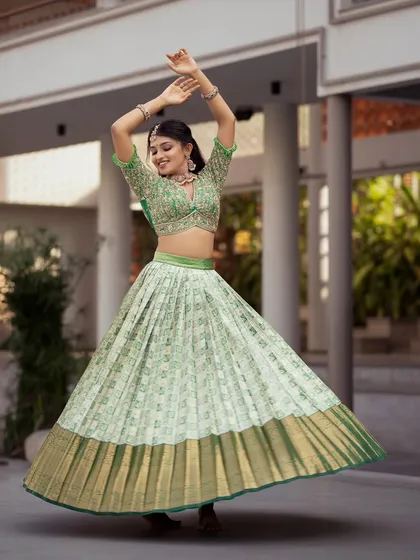 A vision of modern tradition, this Kanchi Pattu half saree in a vibrant pista green captures joyful movement. The pleated Kanchipuram silk skirt creates a beautiful flare, paired with a heavily embroidered blouse, making it a perfect choice for an engagement, sangeet, or half saree ceremony.