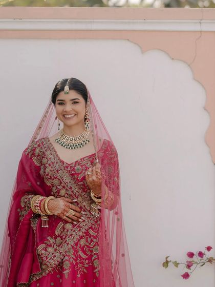 A full-length portrait of the bride in her hot pink lehenga. The makeup is designed to look flawless both up close and from a distance, ensuring she looks perfect in every photo.
