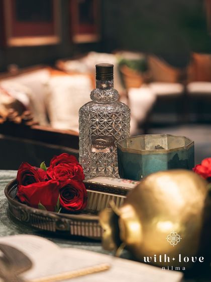 A detail shot of a vintage-style decanter and brass tray with red roses, part of the curated decor for the Raja Ravi Varma-themed sangeet.