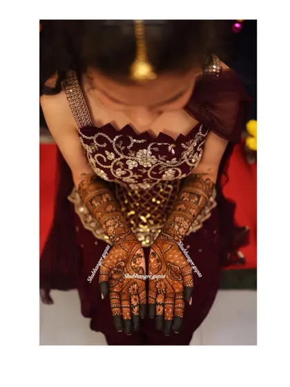 An overhead shot capturing the full splendor of a bridal mehndi design. The dark stain and intricate patterns look stunning against the bride's attire.