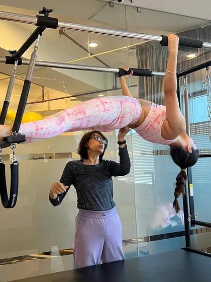 My training will challenge you and help you master advanced movements you may have thought were out of reach. Here, I am spotting a student on the Cadillac, ensuring she feels safe as she builds incredible strength and control.