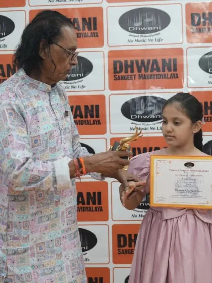 A senior guru presents an award to a young student.