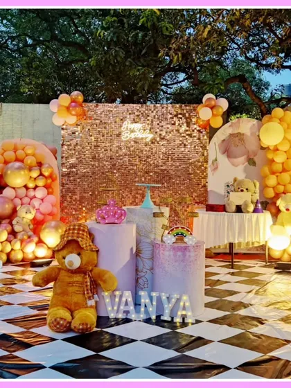 An outdoor teddy bear-themed first birthday. This setup features a checkered floor, a rose gold sequin wall, and adorable teddy bear props.
