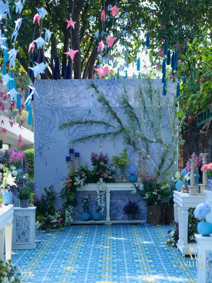 A full view of the dreamy entrance, with the blue tiled floor, hand-illustrated panels, and a ceiling of hanging origami birds and tassels.