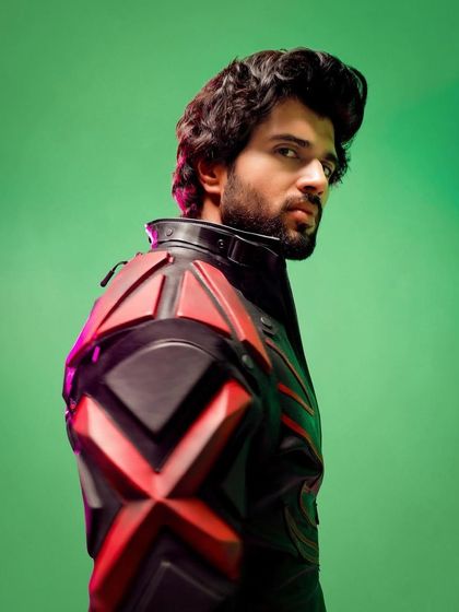 A powerful profile shot of Vijay Deverakonda in the custom Thums Up biker suit. The green screen background hints at the VFX to come, but the suit's strong silhouette already tells a story of action and power.