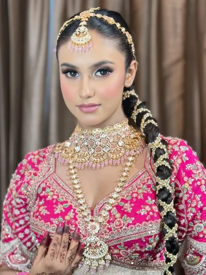 A beautiful portrait of the bride looking directly at the camera, showcasing her flawless base, defined eyes, and the intricate details of her pink-toned jewelry.