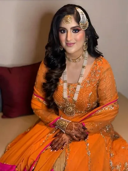The bride seated, her voluminous waves cascading beautifully, completing her royal look.