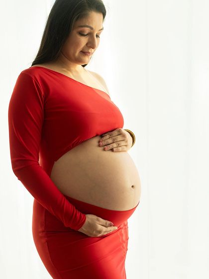 A serene profile shot. The mother-to-be cradles her bare belly in a moment of quiet connection with her baby.