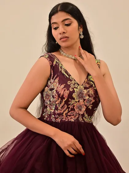 A close-up of a model in a deep purple gown. The makeup is soft and romantic, with a focus on rosy cheeks and a gentle shimmer on the eyes.