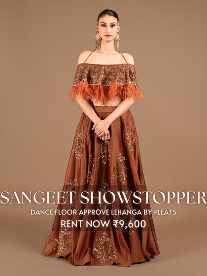 Be a 'Sangeet Showstopper' in this dance-floor-approved lehenga by Pleats. The off-shoulder top with feather details and the rich brown color make it a unique and fashionable choice for an evening of celebration.