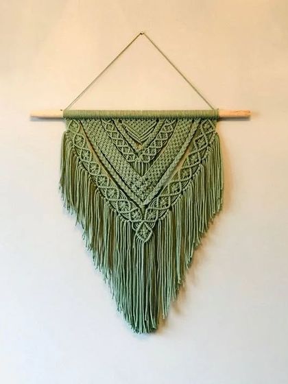 This V-shaped macrame wall hanging in a beautiful sage green adds a touch of handmade art to your walls. We can make it in any color you like.