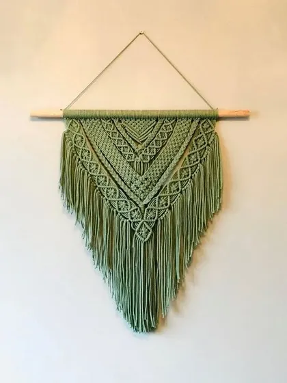 This V-shaped macrame wall hanging in a beautiful sage green adds a touch of handmade art to your walls. We can make it in any color you like.