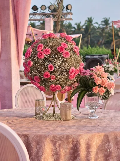 A spherical centerpiece of baby's breath and pink roses. This unique floral structure was designed as a modern and artistic touch for the guest tables.
