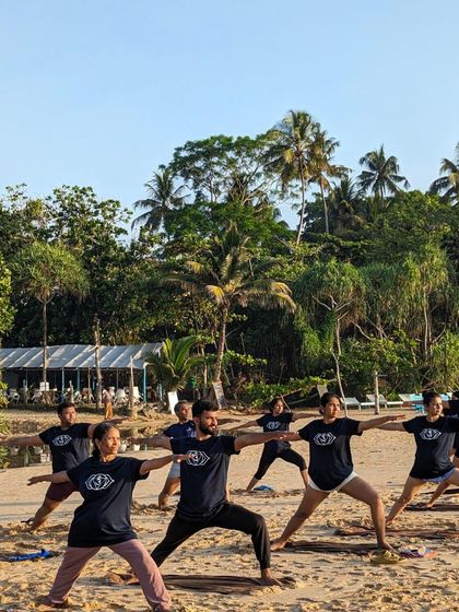 A group of students moving through a warrior sequence on the beach. There is a powerful energy when we practice together, synchronized with the rhythm of nature.