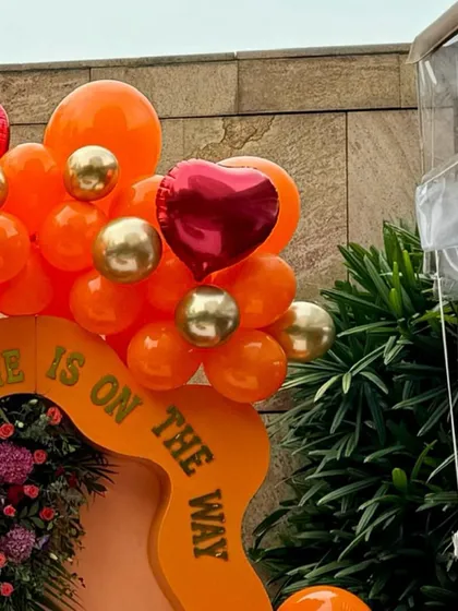A close-up of the balloon artistry from the "Little Cutie" baby shower, showing a mix of orange, red, and gold balloons.