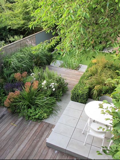 An elevated view of a multi-level deck and patio. We use changes in elevation to create distinct zones for dining and lounging, adding visual interest to a small urban garden.