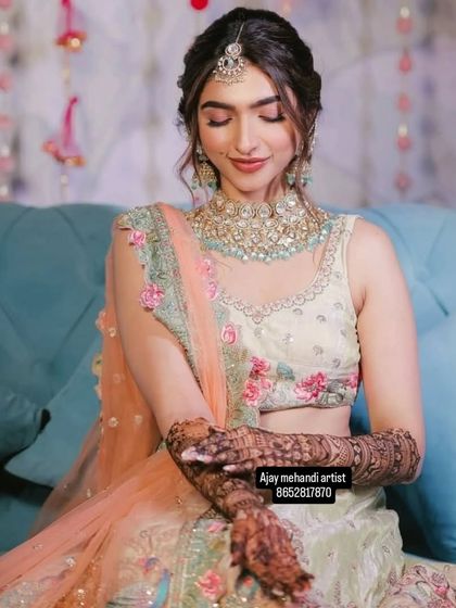 A beautiful bride seated, her hands crossed, showing the full extent of her intricate bridal mehndi.