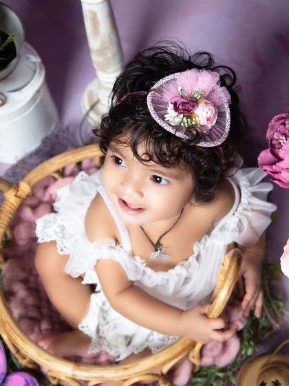 An overhead shot of a baby in a basket, surrounded by a sea of purple and pink flowers, creating a beautiful, artistic portrait.