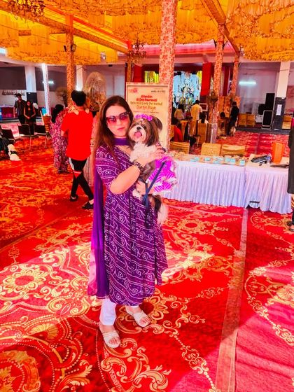 A pet parent and her matching purple-clad Shih Tzu pose for a photo in the middle of the grand, decorated event space, showcasing the scale of our celebration.