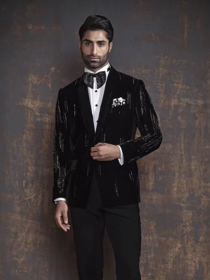 A full-length shot of a black tuxedo jacket with striking silver sequin detailing on the sleeves and lapels. This is a bold choice for a man who wants to make a statement.