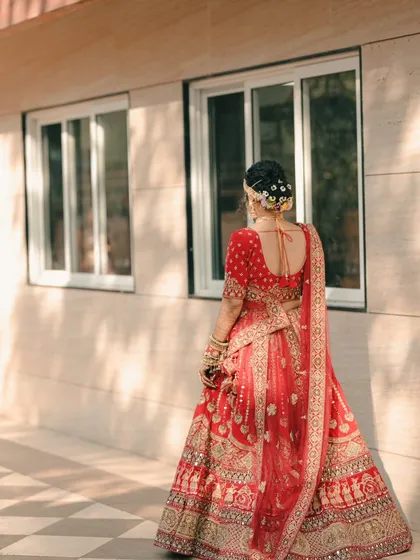 Another angle of the bride's stunning lehenga, capturing the flow and detail of the outfit as she stands in the warm, natural light.