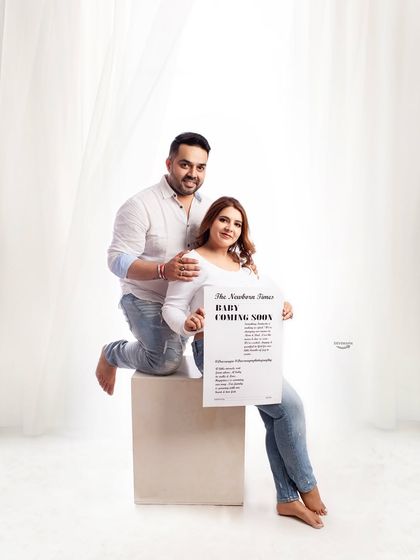 A fun way to announce the big news. This couple uses a 'Baby Coming Soon' newspaper prop in their casual jeans-and-white-shirt session for a creative and memorable photo.