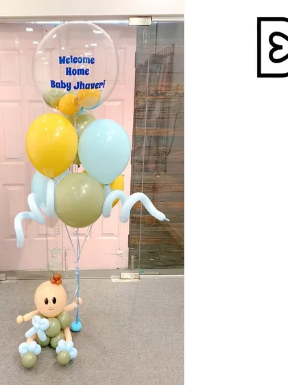 A cute and simple bouquet to welcome home Baby Jhaveri. This arrangement features a little baby sculpture holding a bunch of pastel balloons, including a clear bubble balloon with a personalized welcome message.