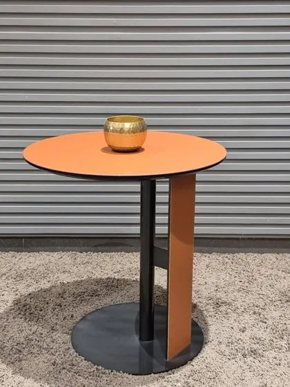 A colorful side table with a bright orange top and a contrasting black and orange base.