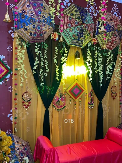 A close-up of the Rajasthani-themed backdrop, showing the detailed mirror work on the umbrellas and the colorful hangings against the draped background.